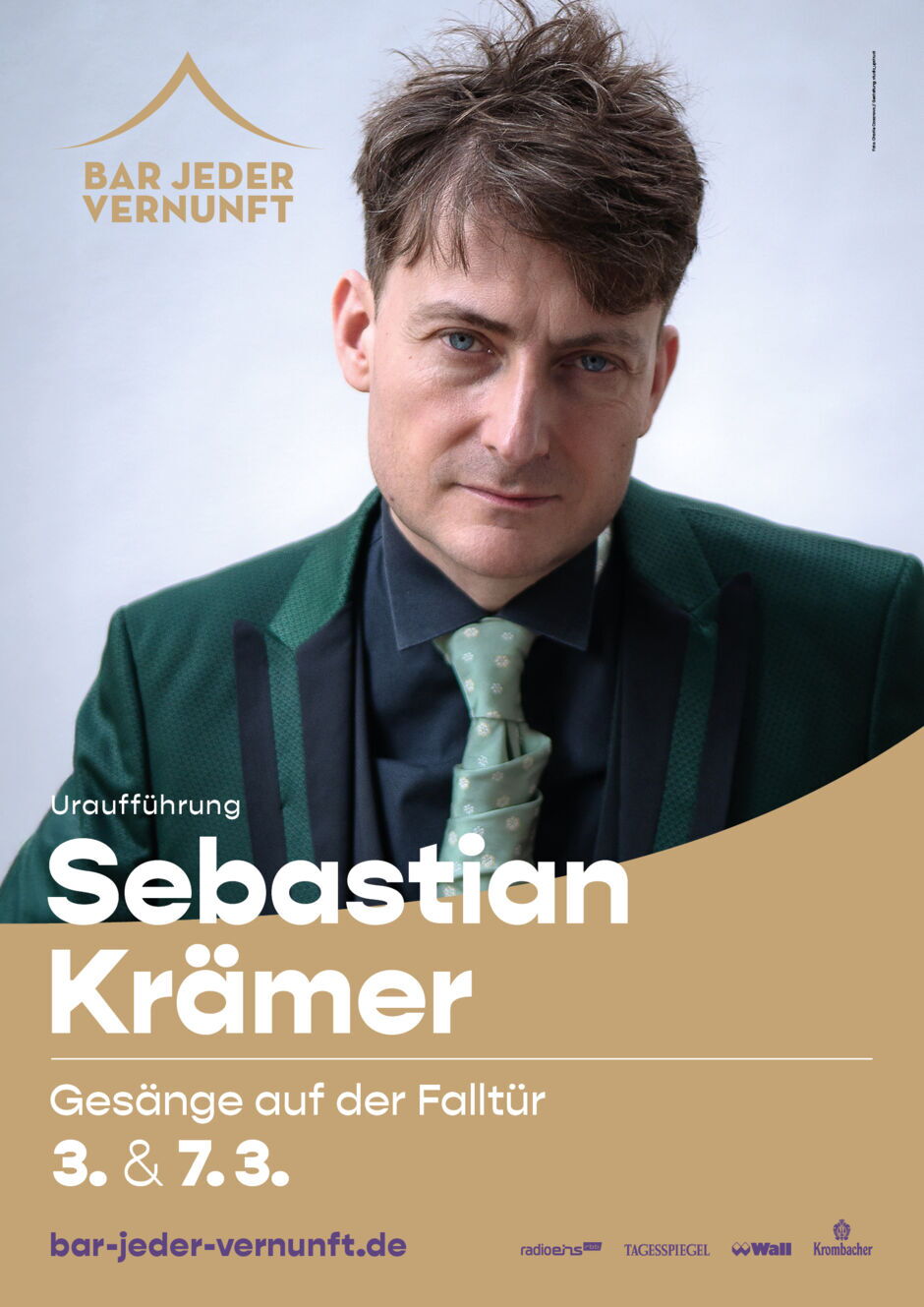 Porträt eines Mannes mit kurzem Haar, dunkelgrünem Sakko, schwarzem Hemd und hellgrüner Krawatte vor hellem Hintergrund mit Text zu einer Show von Sebastian Krämer.